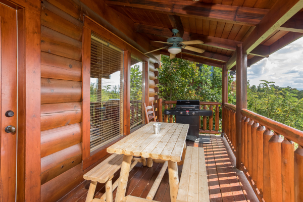 Picnic table with grill on a covered deck at Graceland, a 4-bedroom cabin rental located in Pigeon Forge