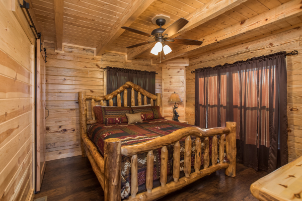 Bedroom with a log bed, night stand, and lamp at The Sugar Shack, a 2 bedroom cabin rental located in Pigeon Forge