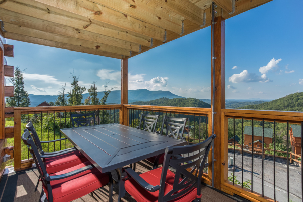 Outdoor dining table for 5 on the covered deck at The Sugar Shack, a 2 bedroom cabin rental located in Pigeon Forge