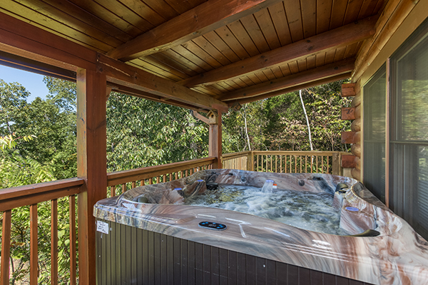 Hot tub on the covered deck surrounded by trees at Lake Life, a 4 bedroom cabin rental located in Sevierville