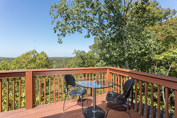 Bistro set on the deck surrounded by trees at Lake Life, a 4 bedroom cabin rental located in Sevierville