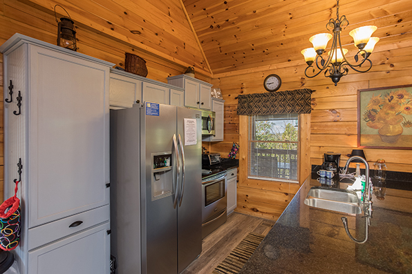 Kitchen with granite counters, stainless appliances, and white cabinets at Lake Life, a 4 bedroom cabin rental located in Sevierville