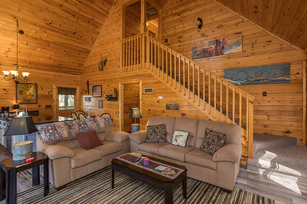 Seating in the living room with the open concept main floor behind at Lake Life, a 4 bedroom cabin rental located in Sevierville