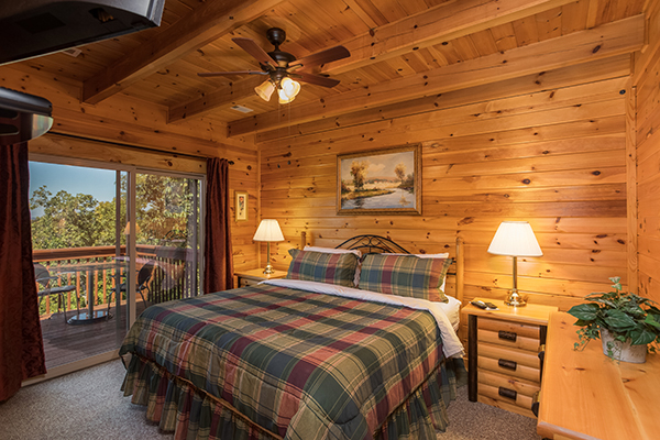 Upstairs bedroom with two night stands and deck access at Lake Life, a 4 bedroom cabin rental located in Sevierville