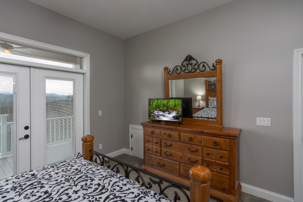 Dresser, TV, and deck access in a bedroom at Summit Glory, a 5 bedroom cabin rental located in Pigeon Forge