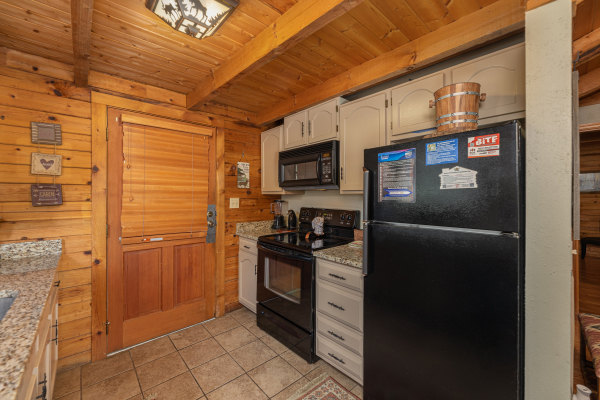 Galley kitchen with black appliances at Snuggle Inn, a 2 bedroom cabin rental located in Pigeon Forge