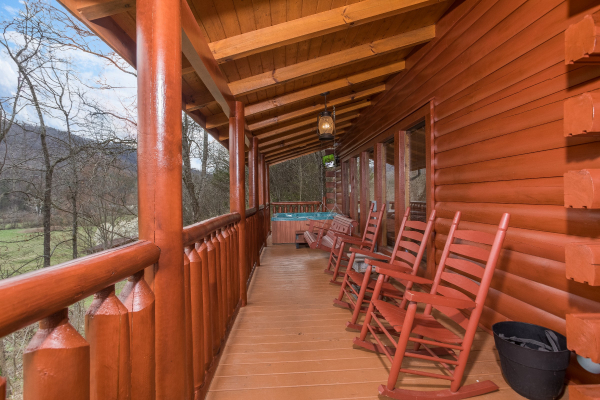 Covered porch with rocking chairs and hot tub at Mountain View Meadows, a 3 bedroom cabin rental located in Pigeon Forge