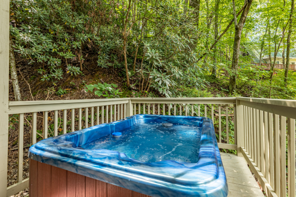 Hot tub on a deck surrounded by trees at License to Chill, a 3 bedroom cabin rental located in Gatlinburg