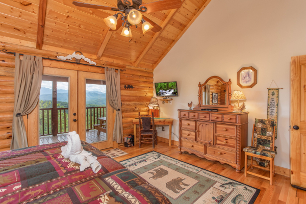 Dresser with mirror, writing desk, TV, and deck access in a bedroom at I Do Love Views, a 3 bedroom cabin rental located in Pigeon Forge