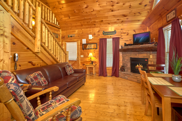 Living room with fireplace, TV, and dining space at Pop's Snuggle Bear, a 1 bedroom cabin rental located in Pigeon Forge