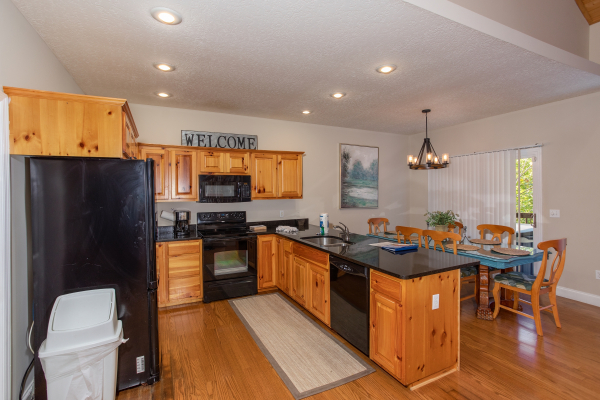 Kitchen with black appliances and dining space at Into the Woods, a 3 bedroom cabin rental located in Pigeon Forge