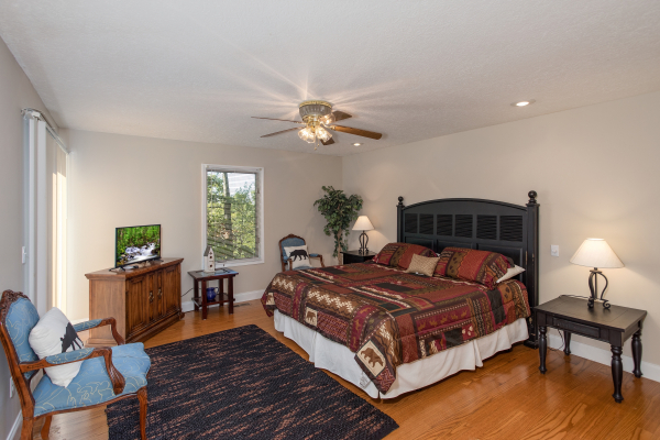 Bedroom with a king bed, TV, and sitting area at Into the Woods, a 3 bedroom cabin rental located in Pigeon Forge