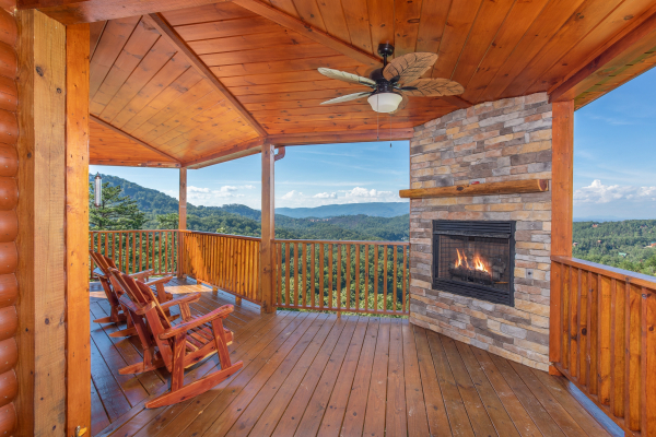 Outdoor fireplace and rocking chairs on the covered deck at Four Seasons Palace, a 5-bedroom cabin rental located in Pigeon Forge