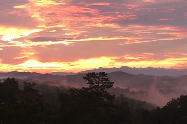 A misty, colorful sunrise from Great View Lodge, a 5-bedroom cabin rental located in Pigeon Forge