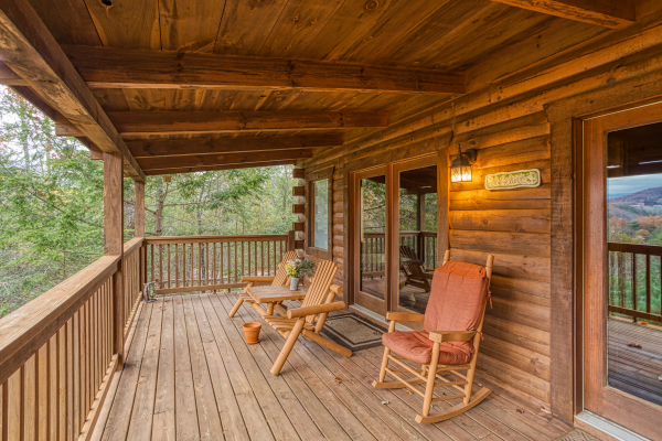 Covered deck with Adirondack bench and rocking chair at Enchanted Evening, a 1-bedroom cabin rental located in Pigeon Forge