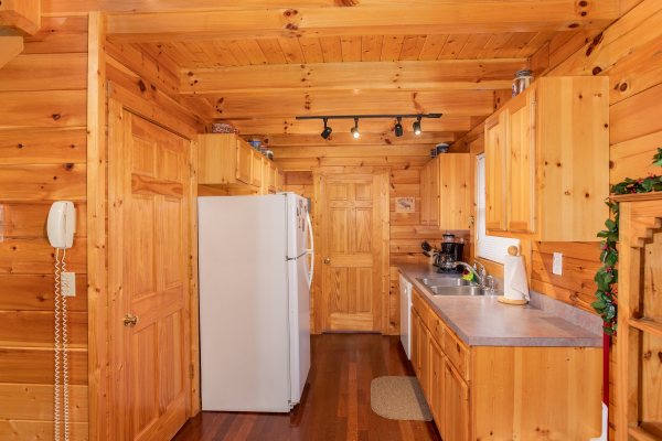 Galley kitchen with white appliances at Enchanted Evening, a 1-bedroom cabin rental located in Pigeon Forge