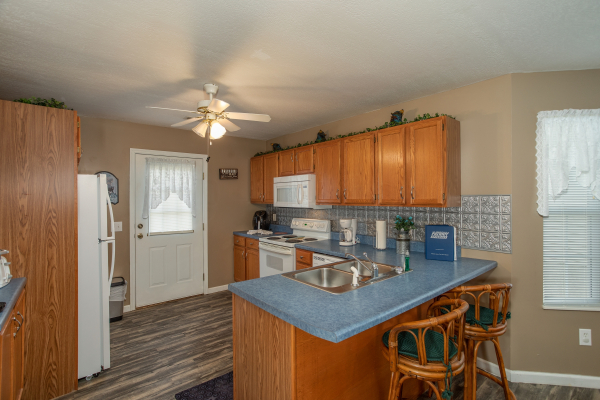 Kitchen with breakfast bar for two and white appliances at Peace at the River, a 3 bedroom cabin rental located in Pigeon Forge