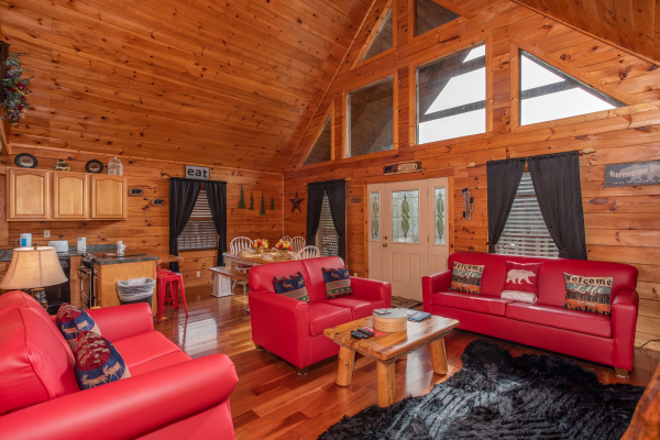 Living room with vaulted ceiling, looking into the dining room and kitchen at Hibernation Station, a 3-bedroom cabin rental located in Pigeon Forge