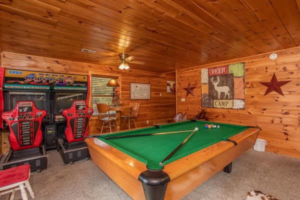 Pool table and driving arcade game in the game room at Hibernation Station, a 3-bedroom cabin rental located in Pigeon Forge