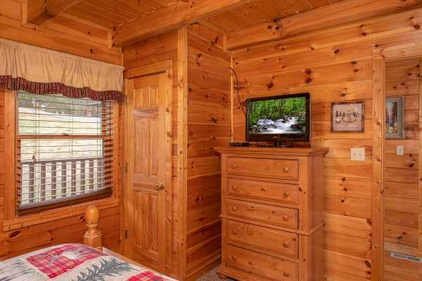 Bedroom with a television and dresser at Hibernation Station, a 3-bedroom cabin rental located in Pigeon Forge