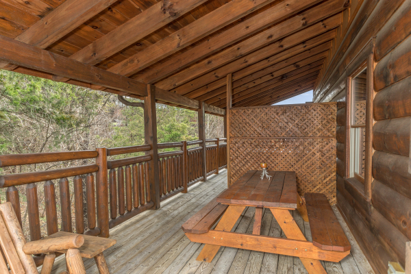 Picnic table on a covered deck at Granny D's, a 2 bedroom cabin rental located in Pigeon Forge
