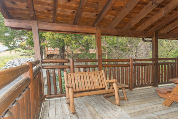 Rocking bench on the covered deck at Granny D's, a 2 bedroom cabin rental located in Pigeon Forge