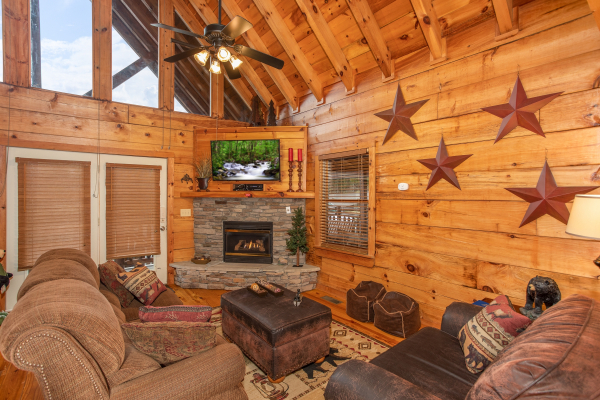 Living room with vaulted ceiling, fireplace, TV, and deck access at Granny D's, a 2 bedroom cabin rental located in Pigeon Forge