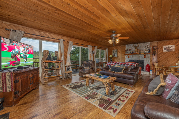 Living room with a fireplace, TV, and large windows at Bearing Views, a 3 bedroom cabin rental located in Pigeon Forge