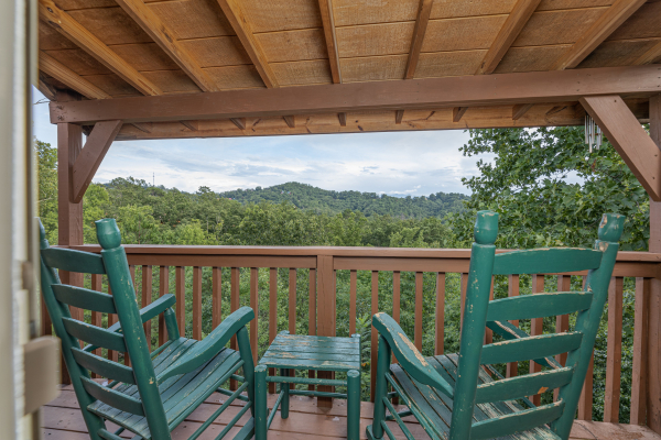 Green rocking chairs on a covered deck at Bearing Views, a 3 bedroom cabin rental located in Pigeon Forge