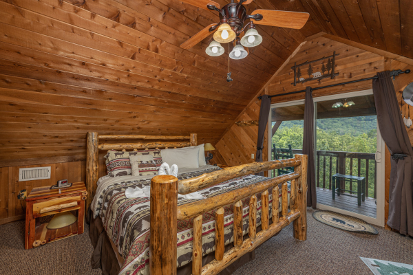 Bedroom with a king log bed, night stands, and deck access at Bearing Views, a 3 bedroom cabin rental located in Pigeon Forge