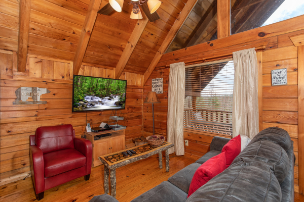 Living room with TV and table at Woodland Chalet, a 1 bedroom cabin rental located in Pigeon Forge