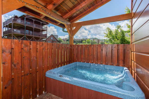Hot tub on a covered porch with privacy fence at Pinot Paradise, a 3 bedroom cabin rental located in Pigeon Forge