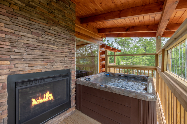 Outdoor fireplace & hot tub on the covered deck at Sawmill Springs, a 3 bedroom rental cabin in Pigeon Forge