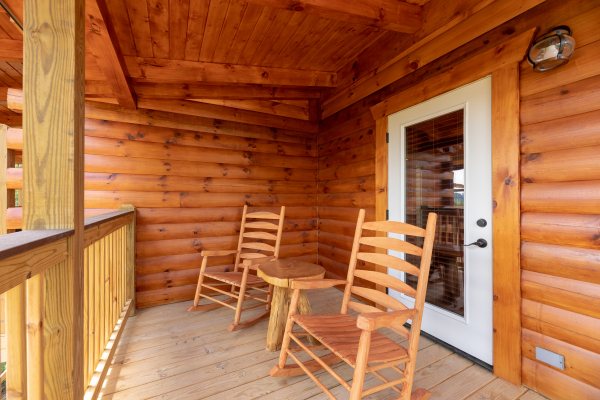 Rocking chairs and a table on the covered deck at Sawmill Springs, a 3 bedroom rental cabin in Pigeon Forge