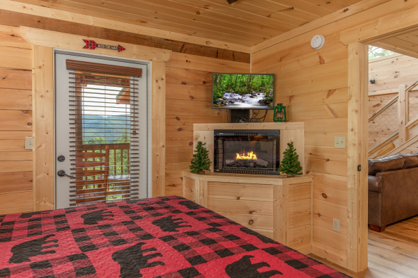 Fireplace, TV, and deck access in a bedroom at Sawmill Springs, a 3 bedroom cabin rental located in Pigeon Forge