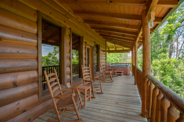 Covered porch with rocking chairs and a hot tub at Mountain Adventure, a 2 bedroom cabin rental located in Pigeon Forge