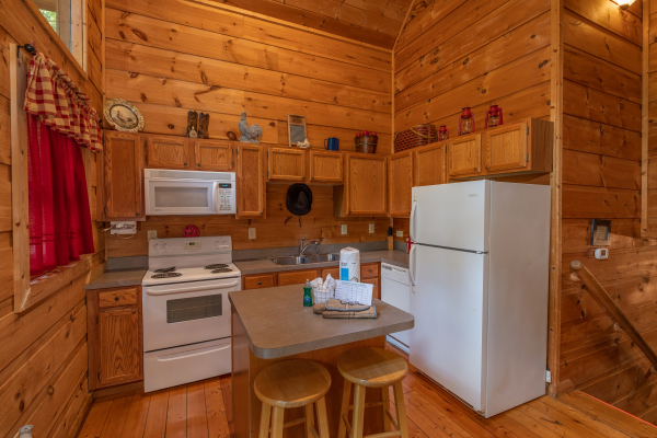 Kitchen with white appliances and breakfast bar with seating for two at Logan's Smoky Den, a 2 bedroom cabin rental located in Pigeon Forge