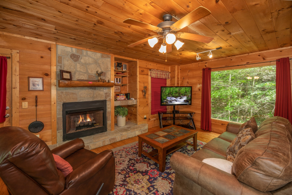Fireplace, TV, and large picture window in the living room at Logan's Smoky Den, a 2 bedroom cabin rental located in Pigeon Forge
