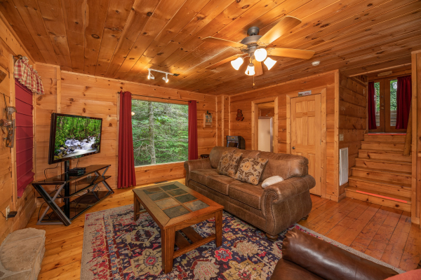 TV, picture window, and sofa in the living room at Logan's Smoky Den, a 2 bedroom cabin rental located in Pigeon Forge