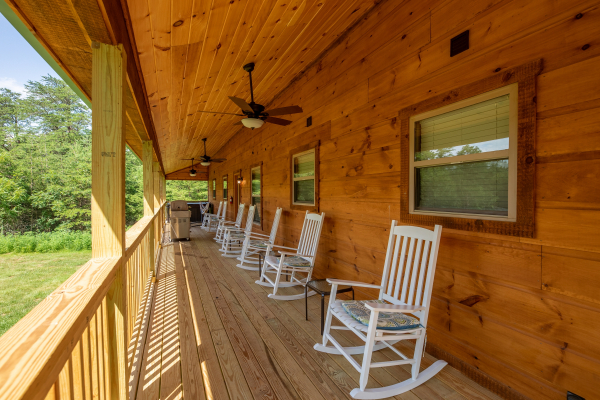Covered porch with ceiling fans and white rocking chairs at Always Dream'n, a 6 bedroom cabin rental located in Pigeon Forge