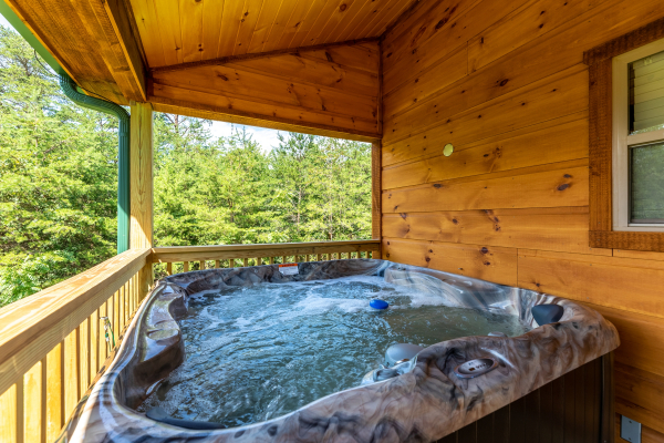 Hot tub on a covered deck at Always Dream'n, a 6 bedroom cabin rental located in Pigeon Forge