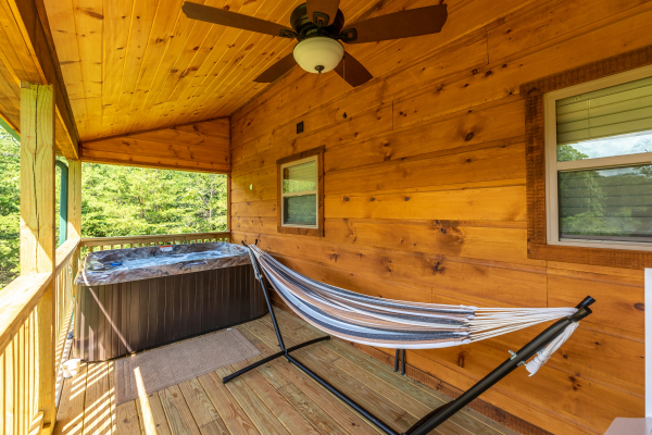 Hammock and hot tub on a covered porch at Always Dream'n, a 6 bedroom cabin rental located in Pigeon Forge