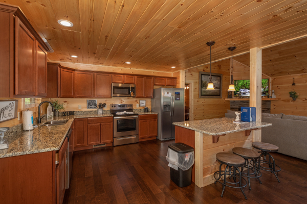 Kitchen with stainless appliances, granite counters, and bar seating for 3 at Always Dream'n, a 6 bedroom cabin rental located in Pigeon Forge