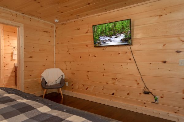 Chair and wall mounted TV in a bedroom at Always Dream'n, a 6 bedroom cabin rental located in Pigeon Forge