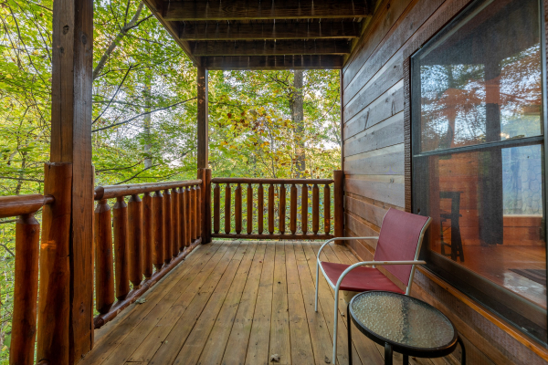 Deck chair and small table on a covered deck at Firefly Ridge, a 2 bedroom cabin rental located in Pigeon Forge