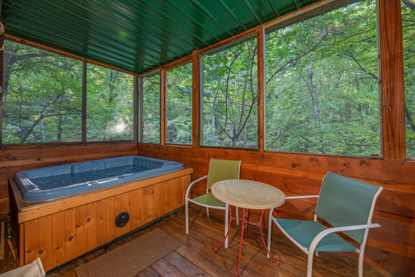 Hot tub and bistro set on a screened in porch at Firefly Ridge, a 2 bedroom cabin rental located in Pigeon Forge