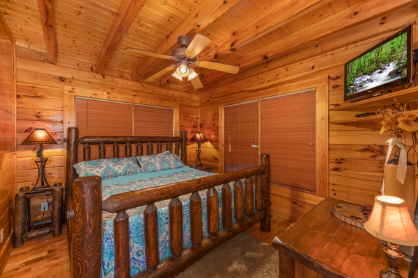 Bedroom with king log bed, two night stands, two lamps, and a TV at Rocky Top Retreat, a 2 bedroom cabin rental located in Pigeon Forge