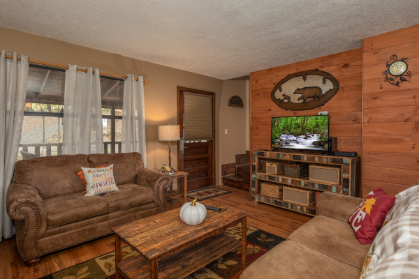 TV, sofa, and loveseat in the living room at Misty Mountain Sunrise, a 3 bedroom cabin rental located in Pigeon Forge