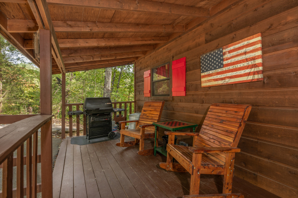 Gas grill and chairs on a covered deck at Misty Mountain Sunrise, a 3 bedroom cabin rental located in Pigeon Forge