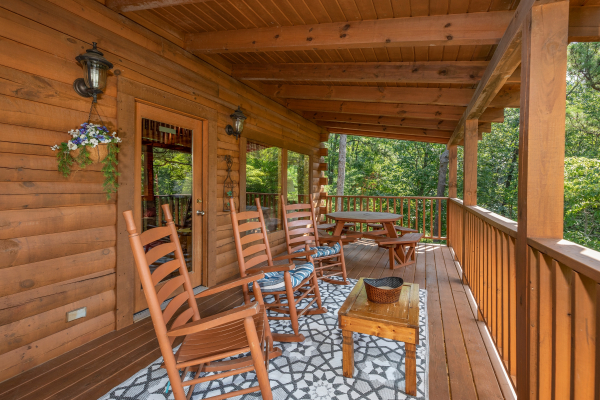 Rocking chairs and a picnic table on the covered deck at Majestic Mountain, a 4 bedroom cabin rental located in Pigeon Forge